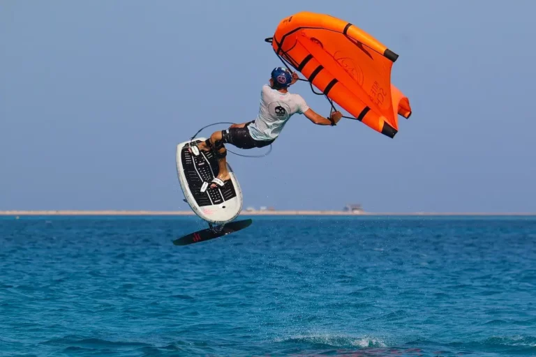 wingfoiler jumps with orange wing in Egypt