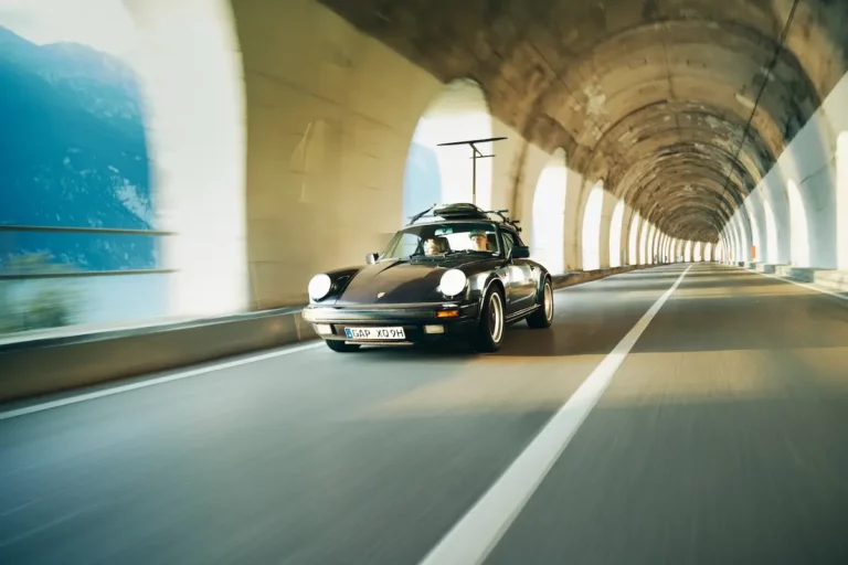 porsche 911 g-modell mit surfboard fährt durch gardasana tunnel