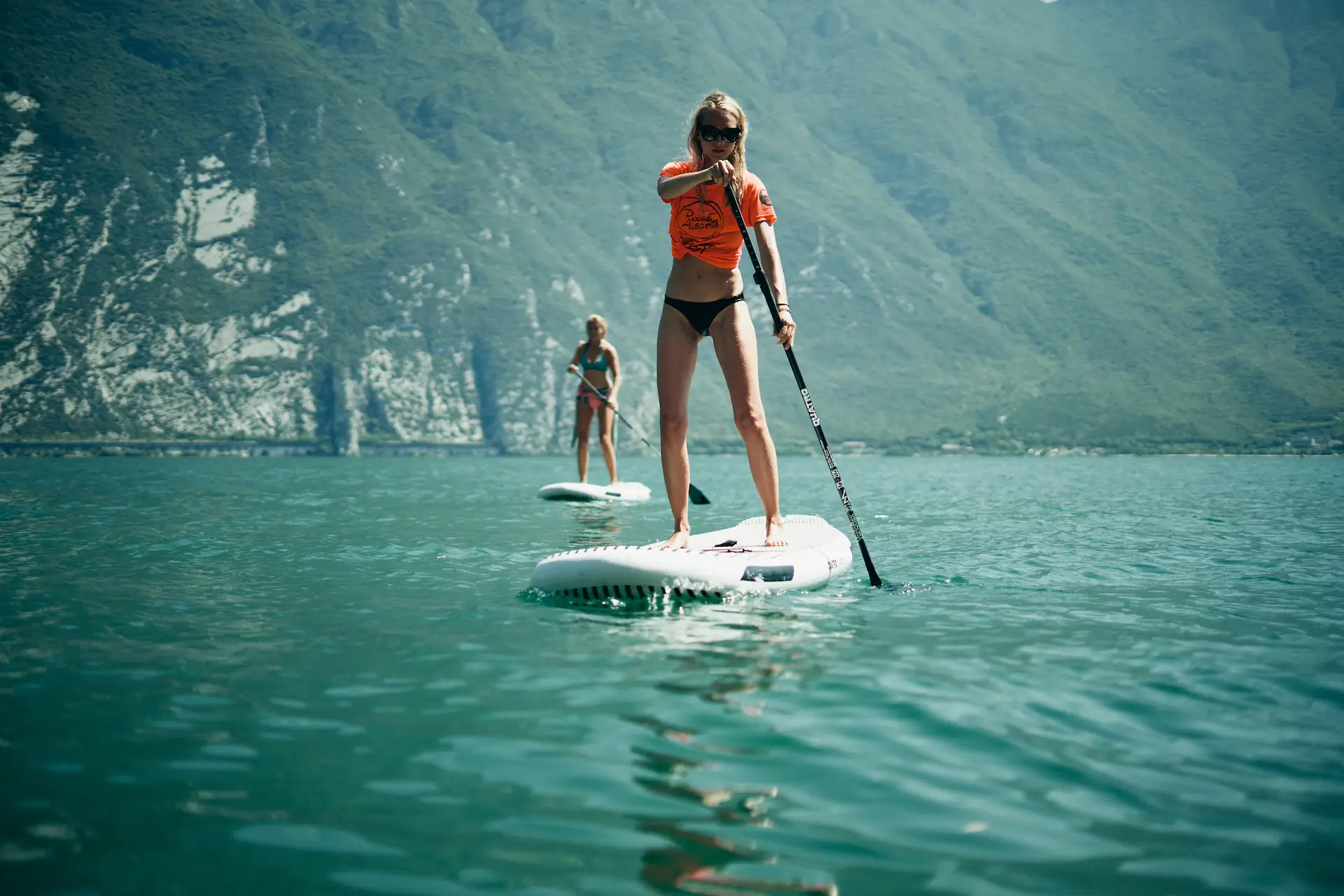 two blonde women stand up paddling at Lake Garda