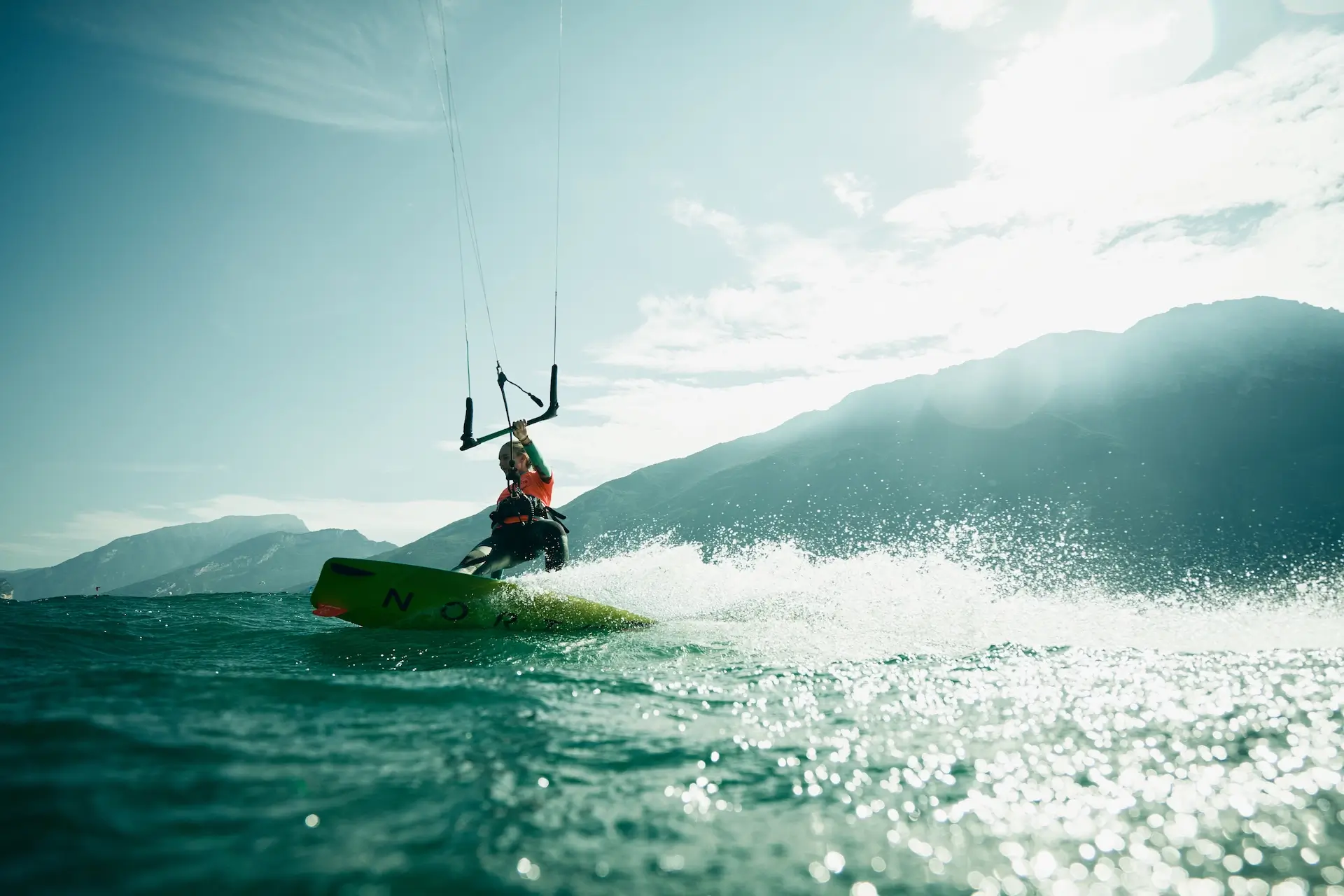 Blonde Kitesurfin gleitet mit gelben Kiteboard über den Gardasee