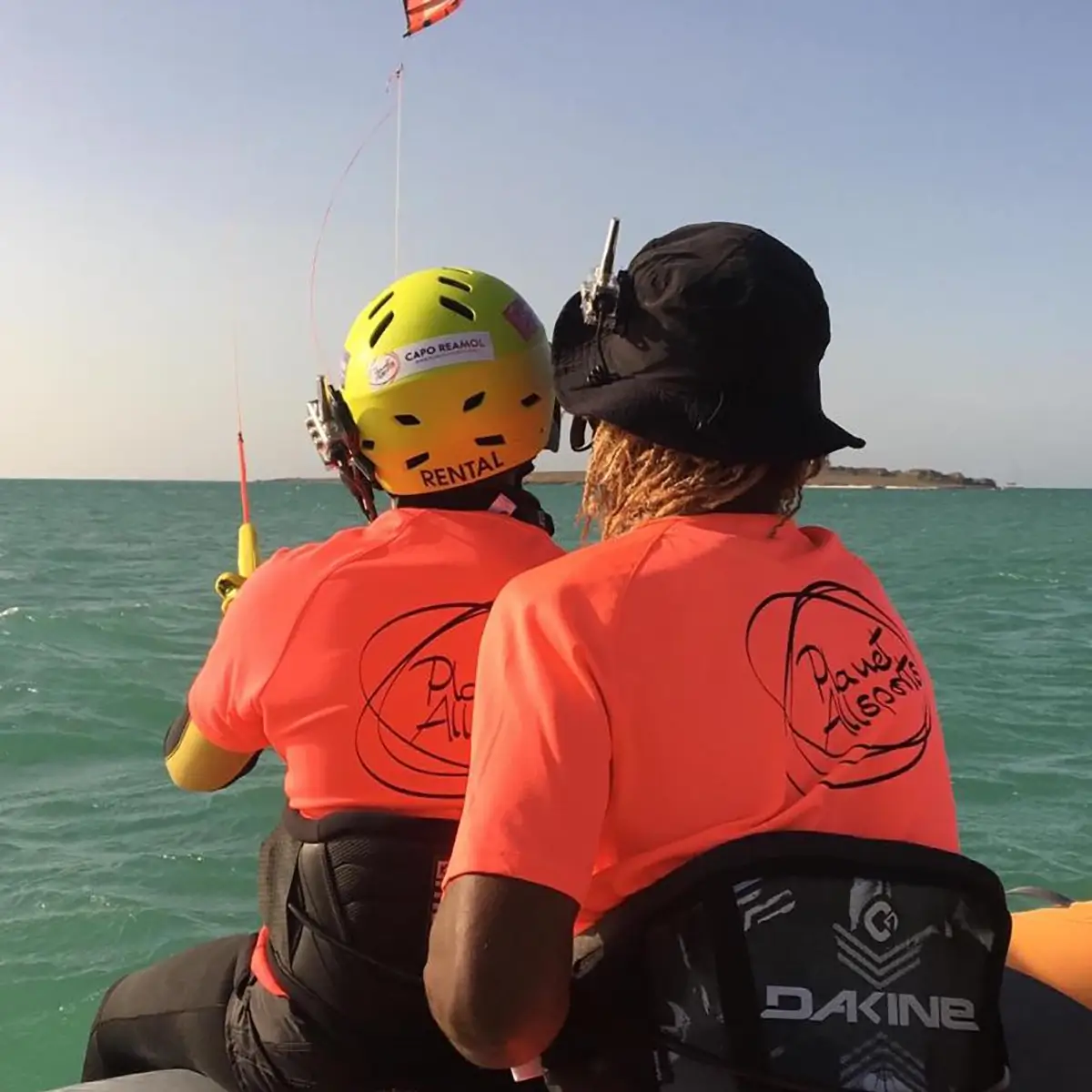 Kitelehrer mit Kiteschüler mit orangen Lycrashirts und Funkheadset