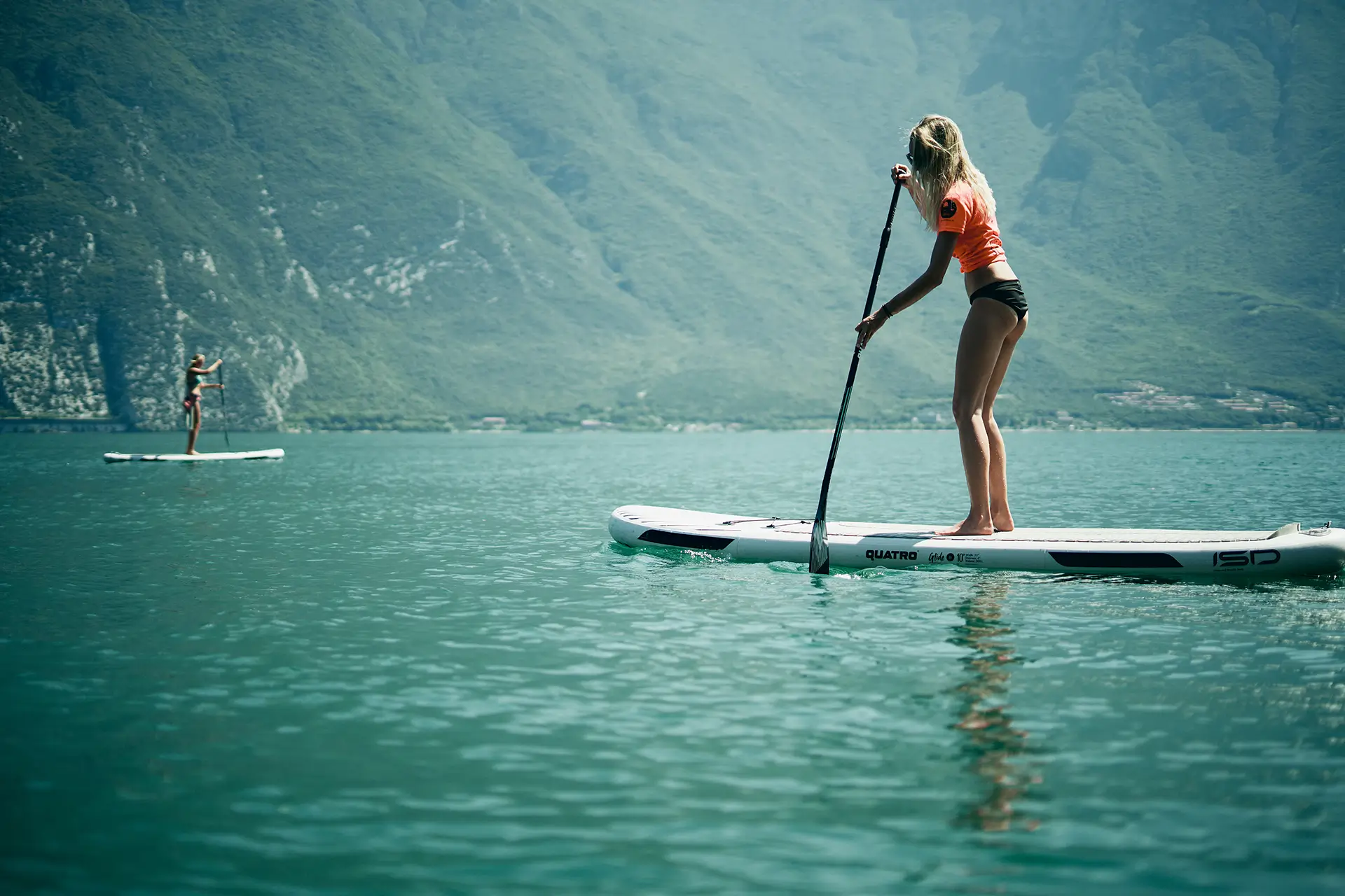 blonde Frau paddelt mit SUP Brett am Gardasee