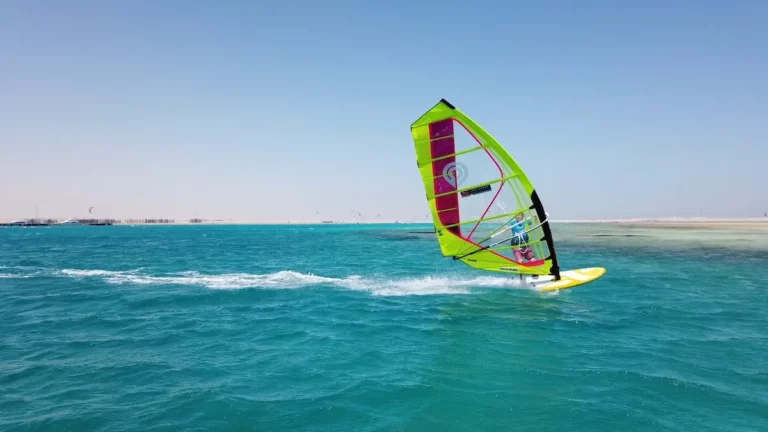windsurfer plaining at the Red Sea in blue water with yellow sail and board