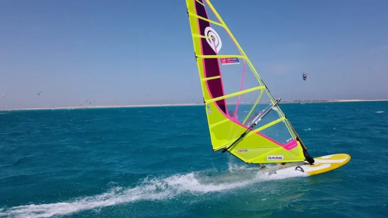 windsurfer with yellow sail and board is going fast on blue water