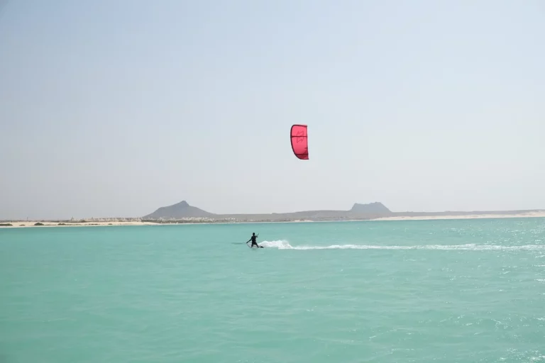 Kiter mit rotem Kite gleitet über türkises Wasser auf Boavista