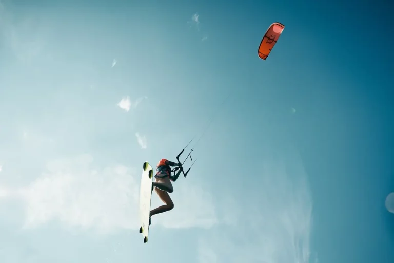 Kitesurferin mit roten Kite springt