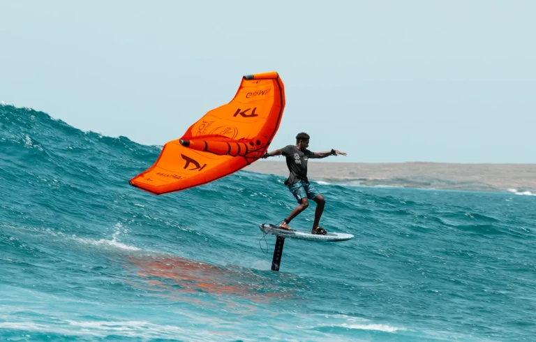 wingfoiler with orange wing in a big wave